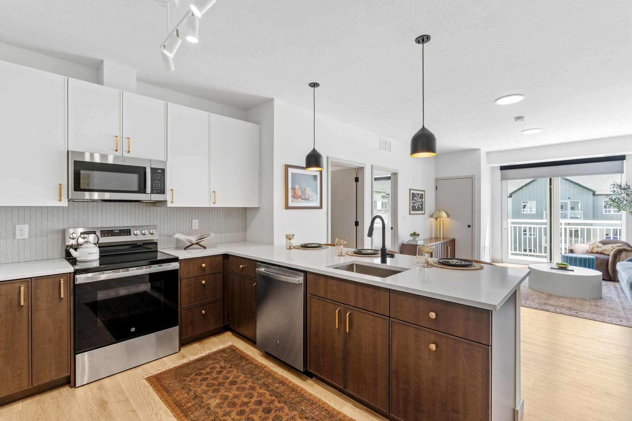 Open kitchen layout leading into bright living space with large window and balcony access