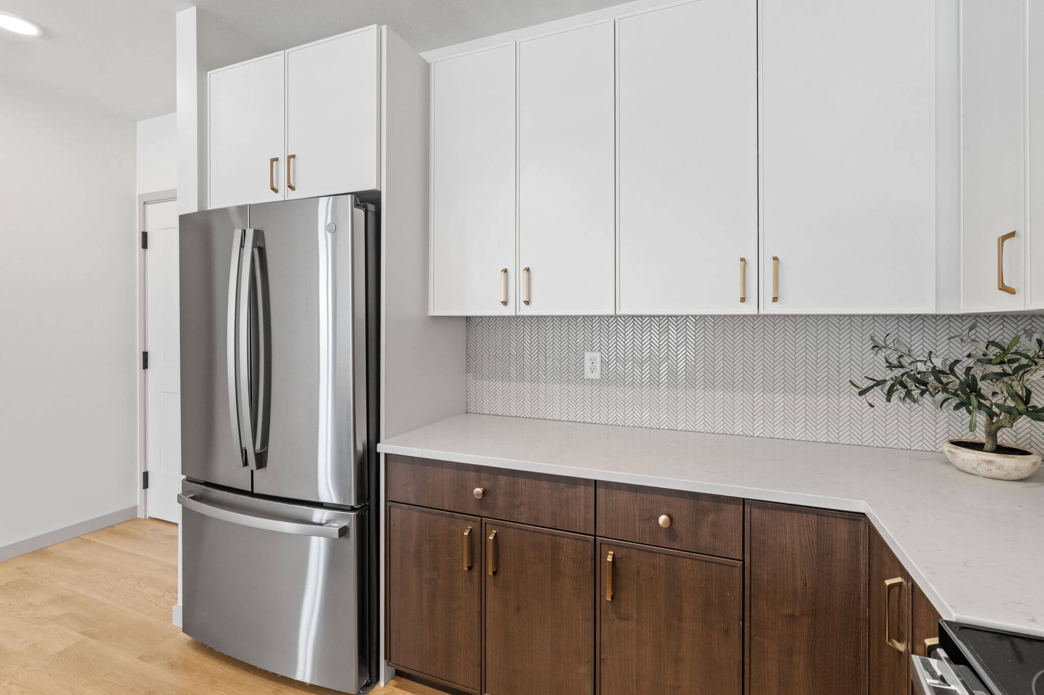 White upper cabinets with gold hardware and chevron tile backsplash at Rye Apartments