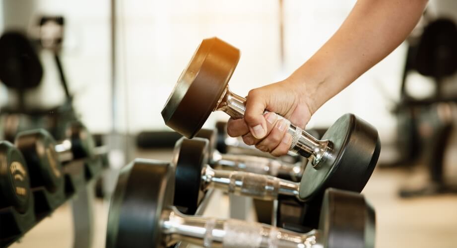 A man grabbing a dumbell in the gym.