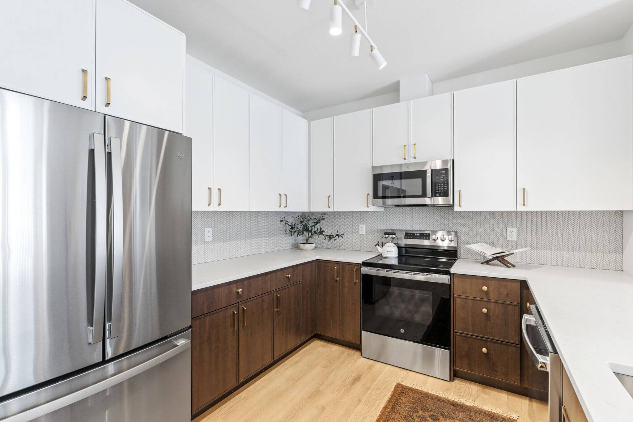 U-shaped kitchen with stainless steel appliances and white and wood-tone cabinets