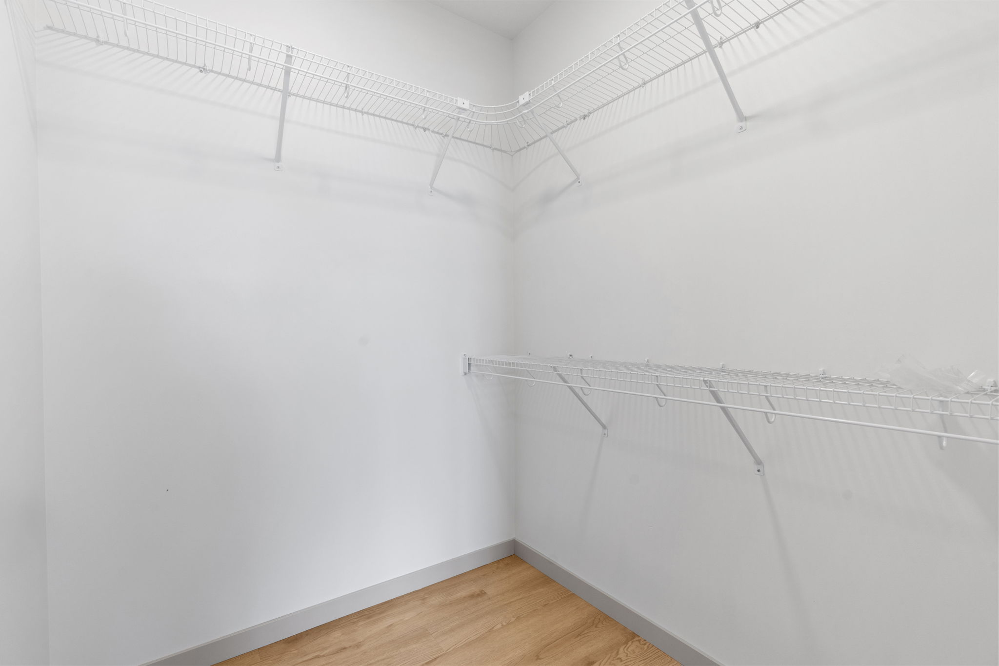 Corner view of walk-in closet with white wire shelving and clean white walls
