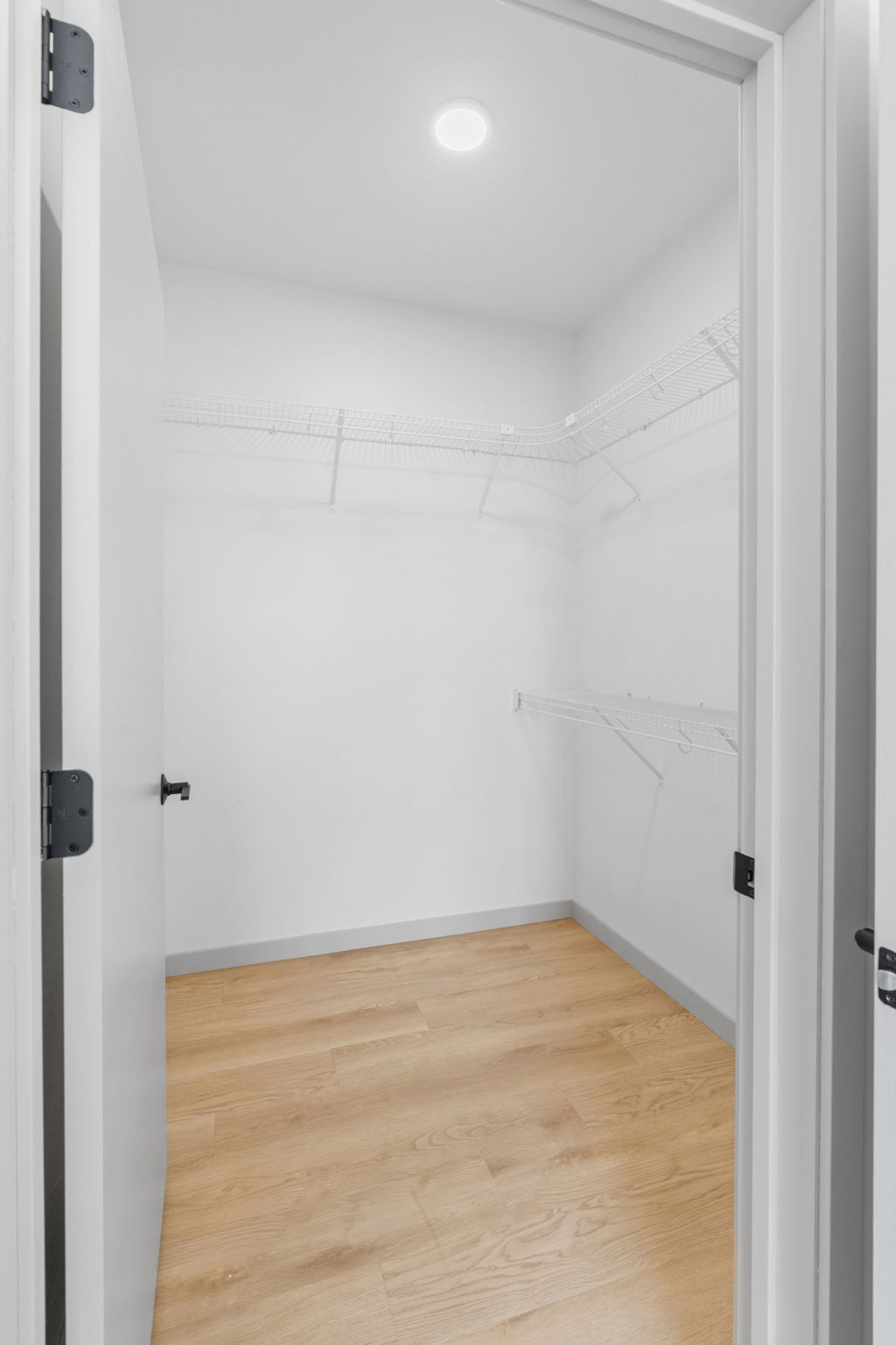 Spacious walk-in closet with wire shelving and natural wood floors