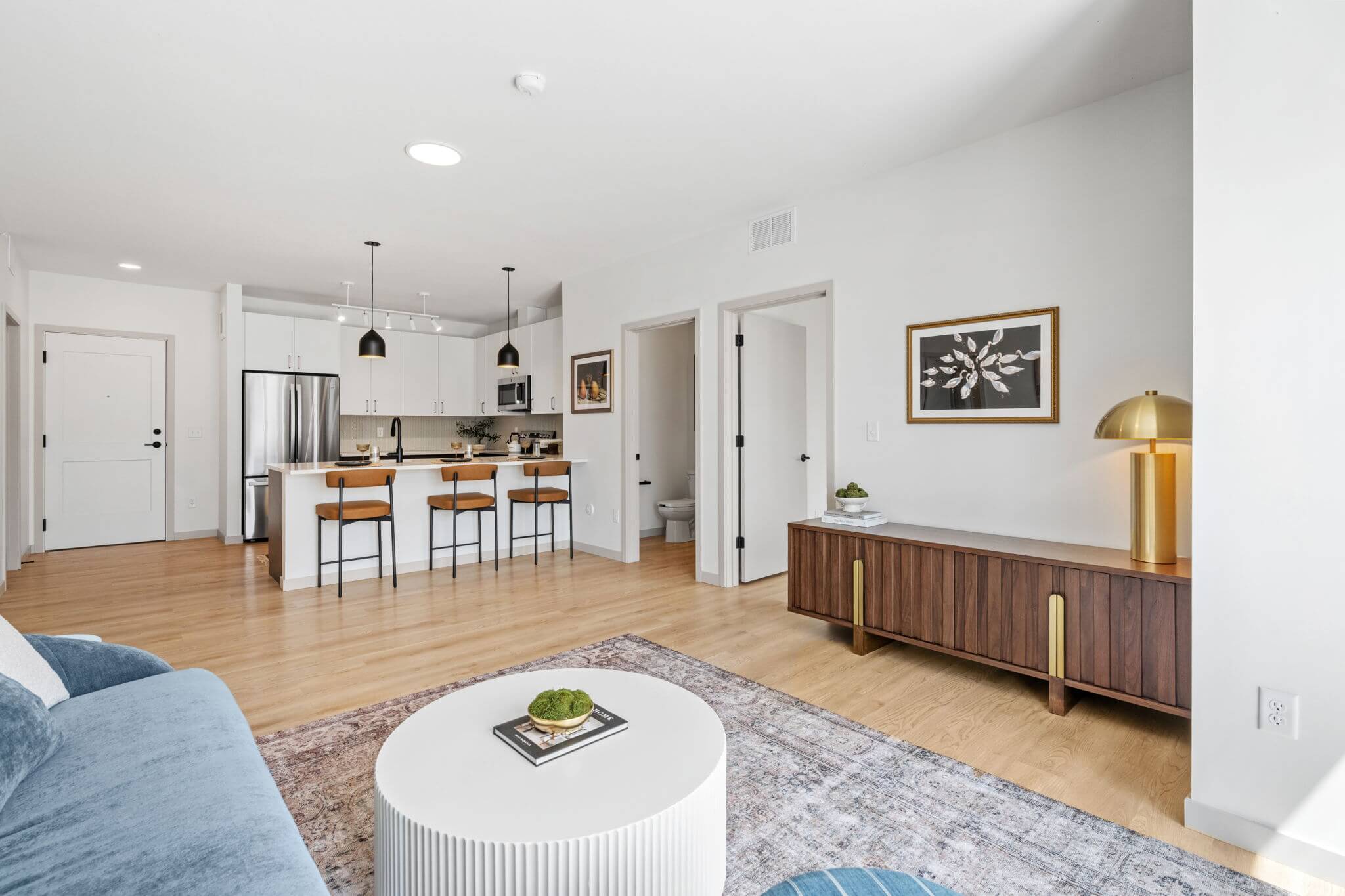 Open concept living room and kitchen with modern decor and bar seating at Rye Apartments