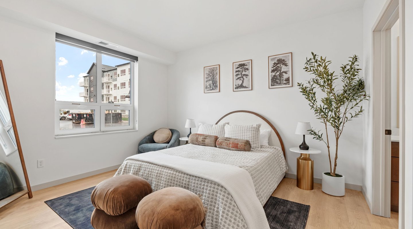 rendering of a bedroom with modern furnishings and ample light at Rye Apartments