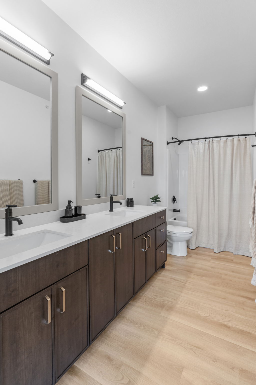 Bathroom with double sink vanity, large mirror, and shower curtain at Rye Apartments