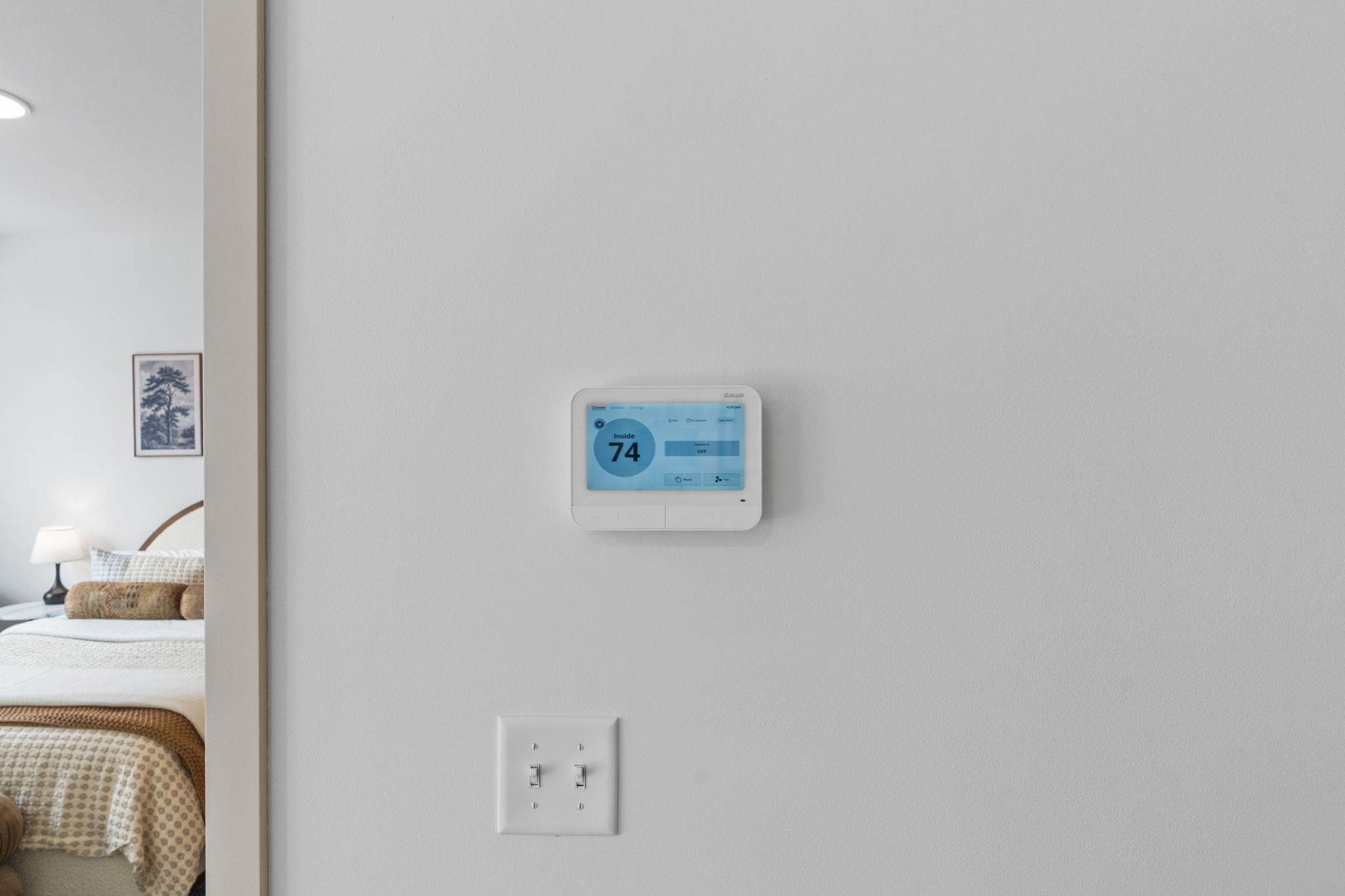 Wall-mounted smart thermostat set to 74 degrees inside Rye Apartments