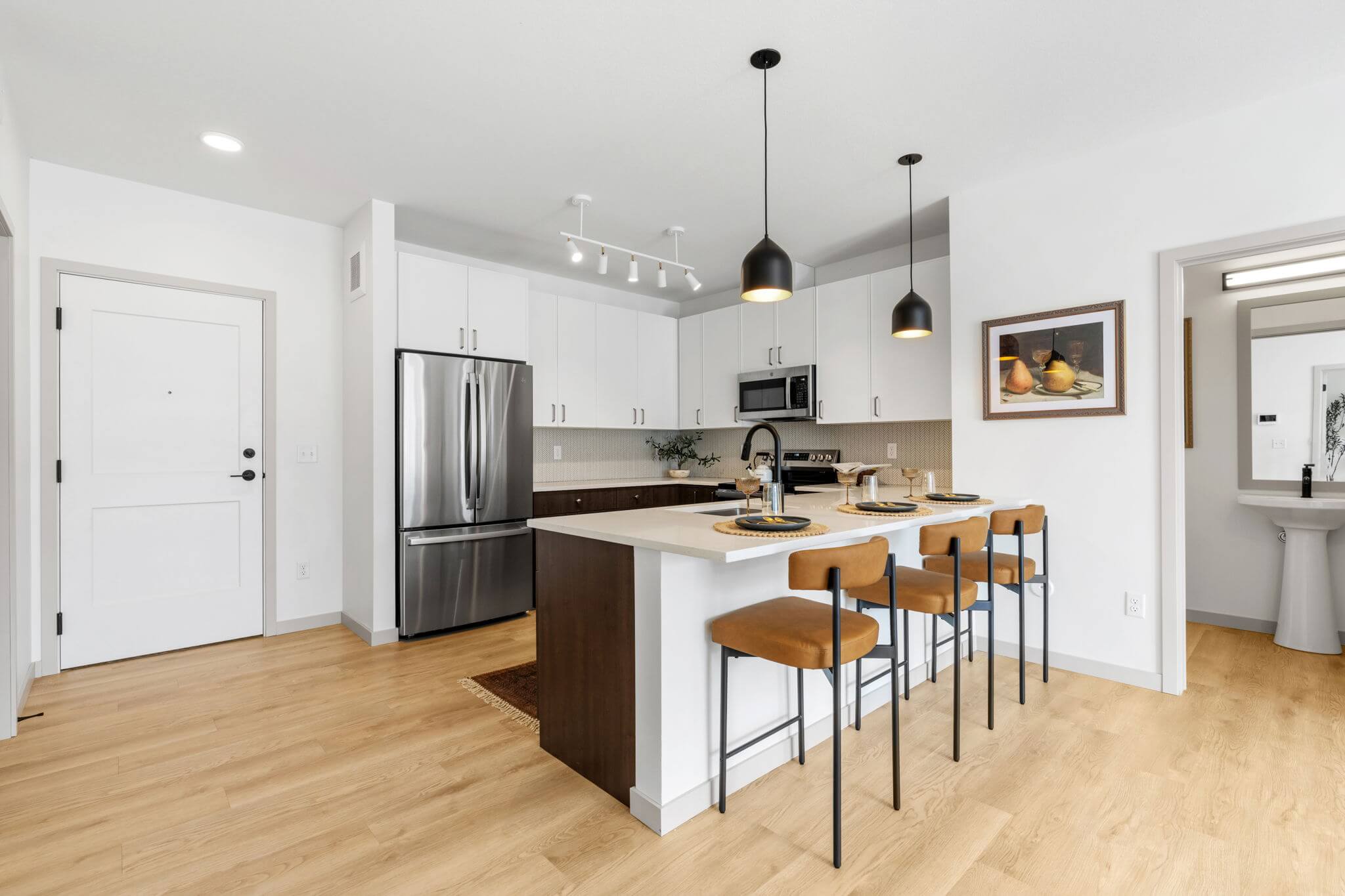 Kitchen with bar seating, pendant lights, and stainless steel refrigerator at Rye Apartments